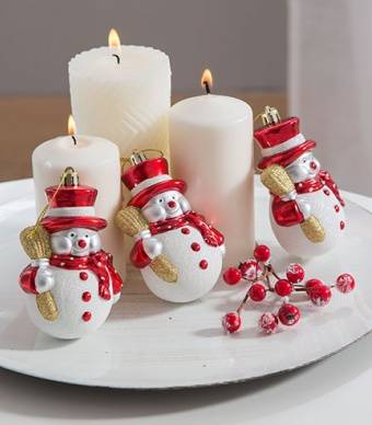 Decoração de mesa feita com velas brancas e enfeites em forma de bonecos de neve 